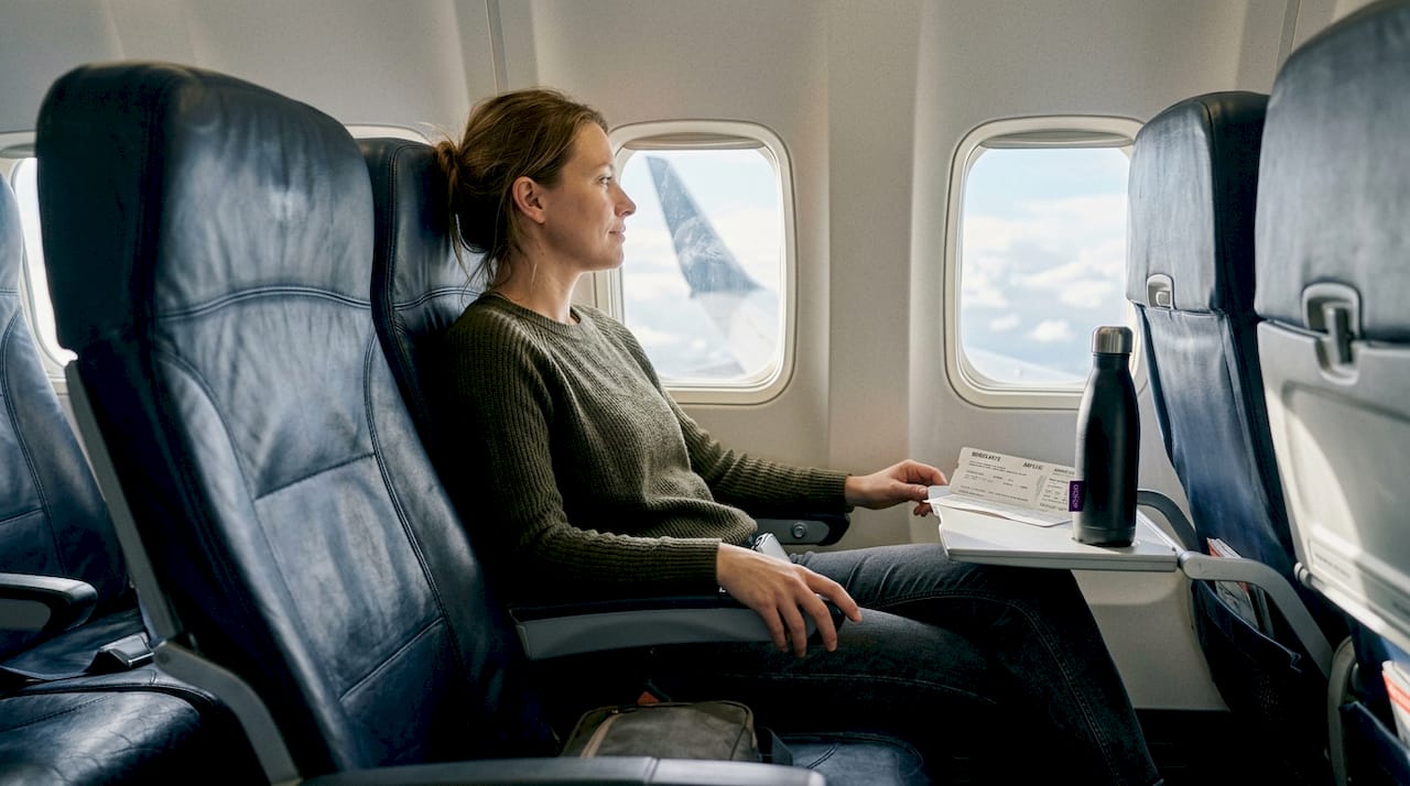 Ein Reisender lehnt sich entspannt in seinem Flugzeugsitz zurück und genießt die ruhige Atmosphäre an Bord.